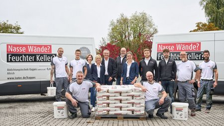 ISOTEC Team posiert vor Transportern mit Baumaterial.